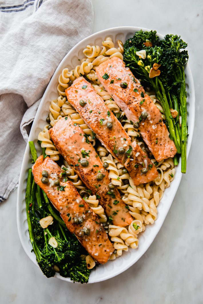 salmon piccata dinner on platter with broccolini and pasta