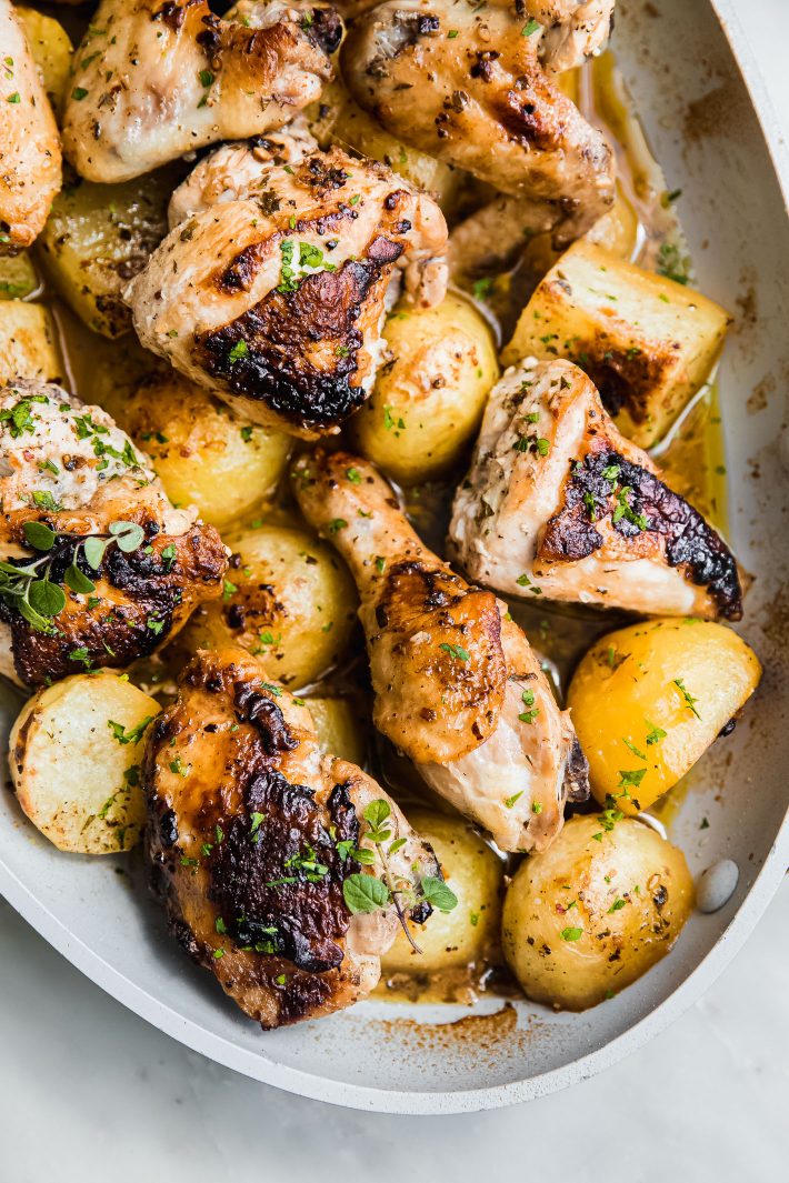 greek chicken and potatoes in pan topped with oregano