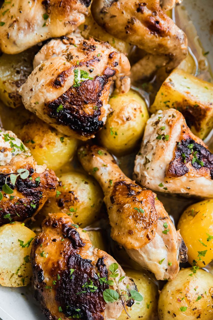 greek lemon chicken in pan on top of roasted potatoes