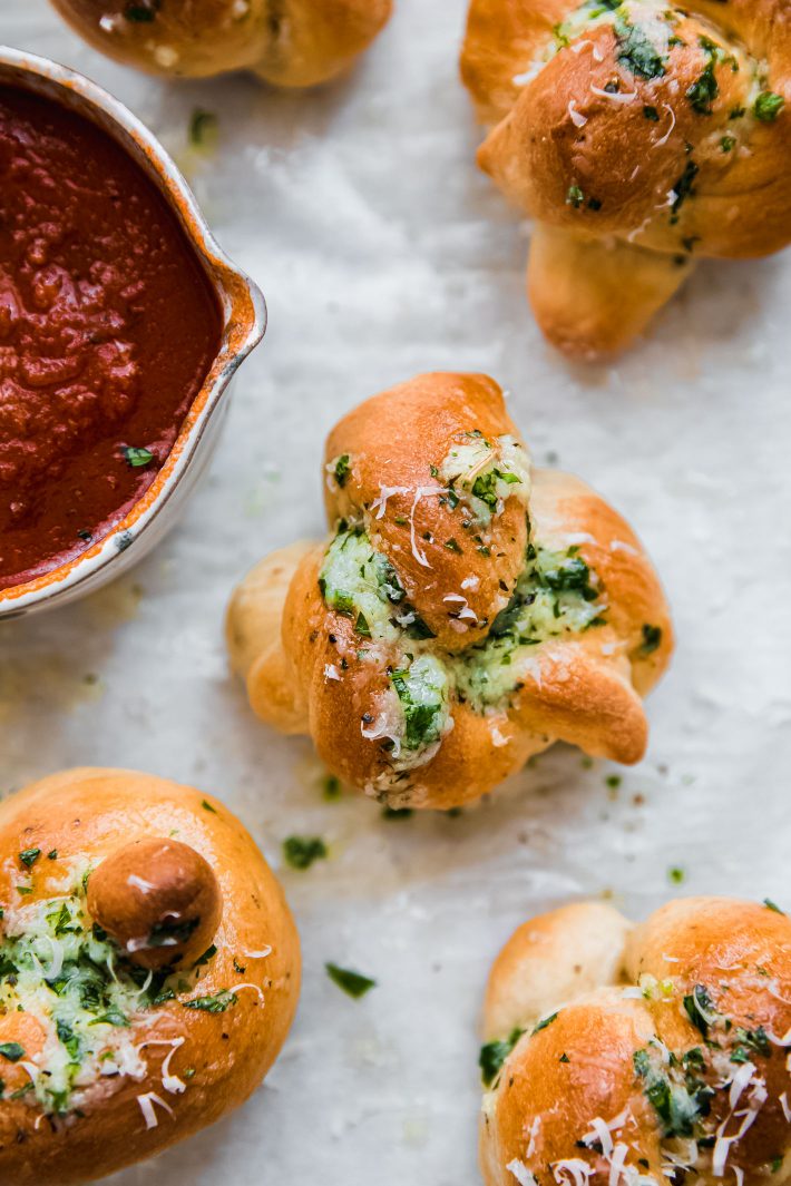 garlic knots on parchment with pizza sauce in bowl