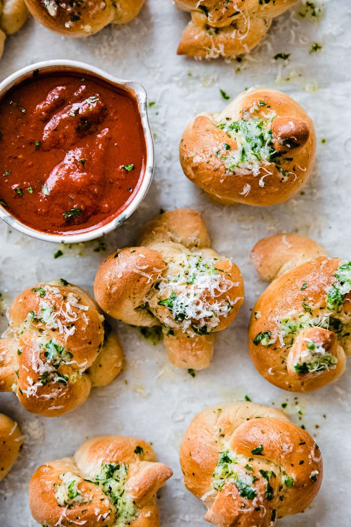 Garlic knots on parchment with pizza sauce