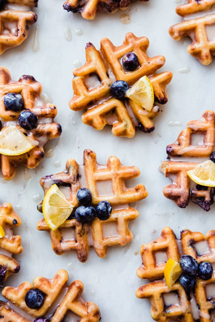 marble board with prepared glazed waffles topped with lemon wedges and fresh blueberries