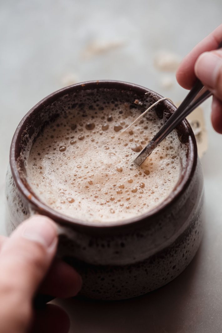 hand on mug and spoon stirring latte