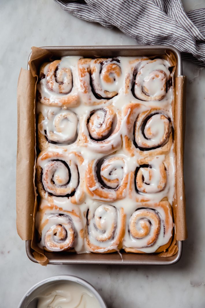 prepared cinnamon rolls in a baking dish on white marble surface