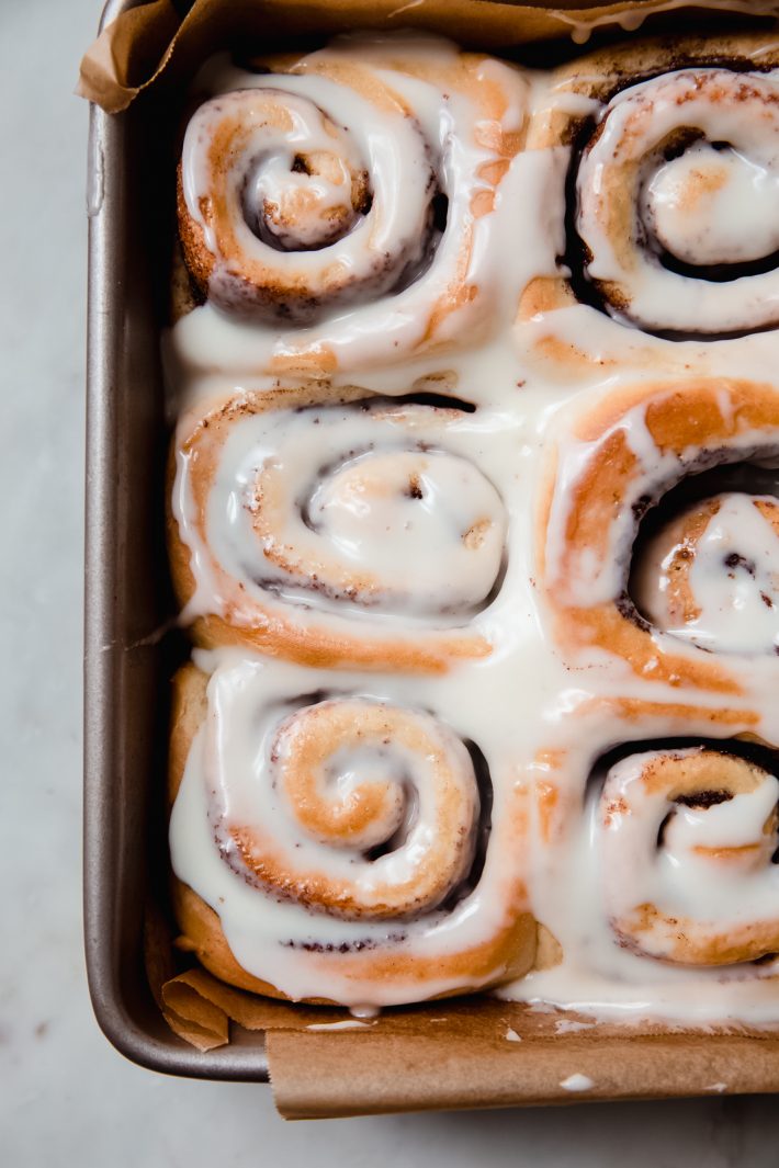 prepared cinnamon rolls in baking pan topped with cream cheese icing