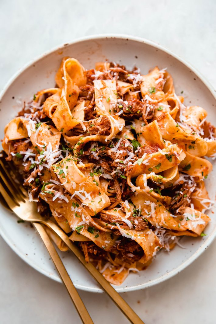 beef ragu with pappardelle pasta on a plate with fork and spoon