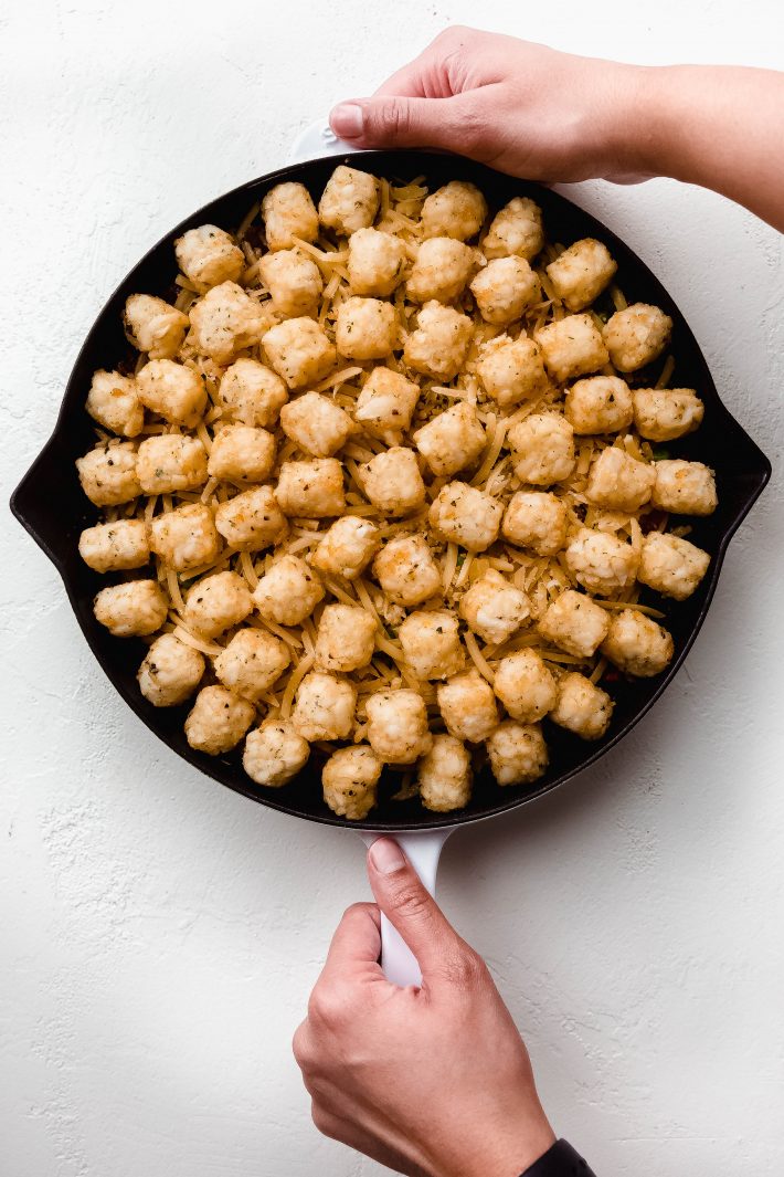 skillet with cottage pie filling topped with frozen potato puffs