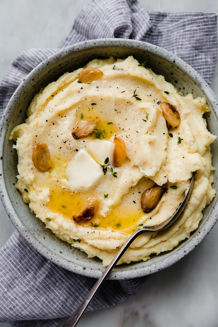 bowl of mashed potatoes with spoon on striped towel