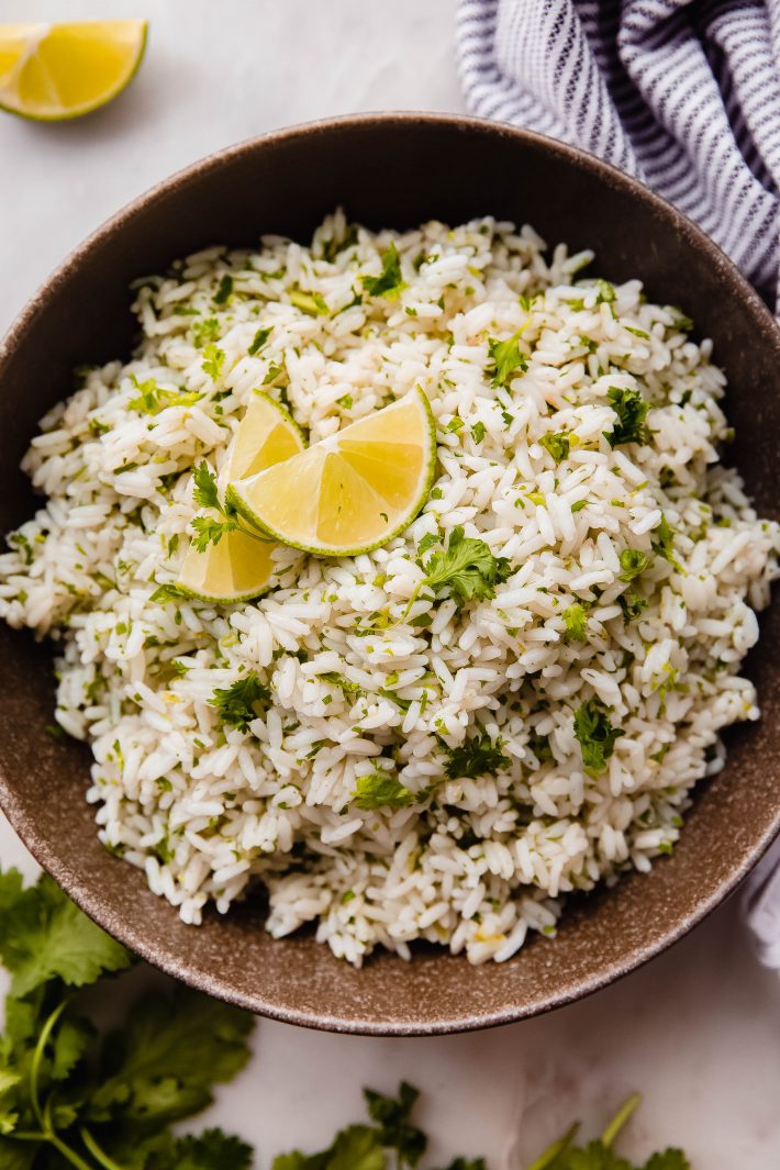 rice with cilantro and lime in olive bowl with lime wedges