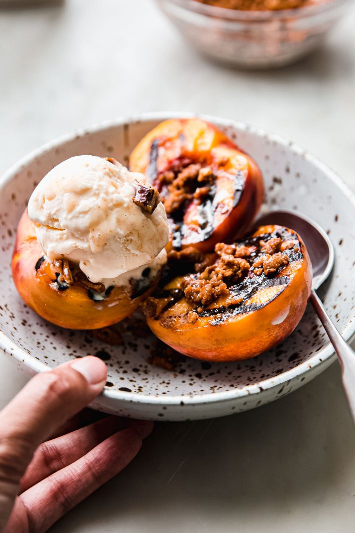 grilled peaches in bowl topped with crumble and ice cream