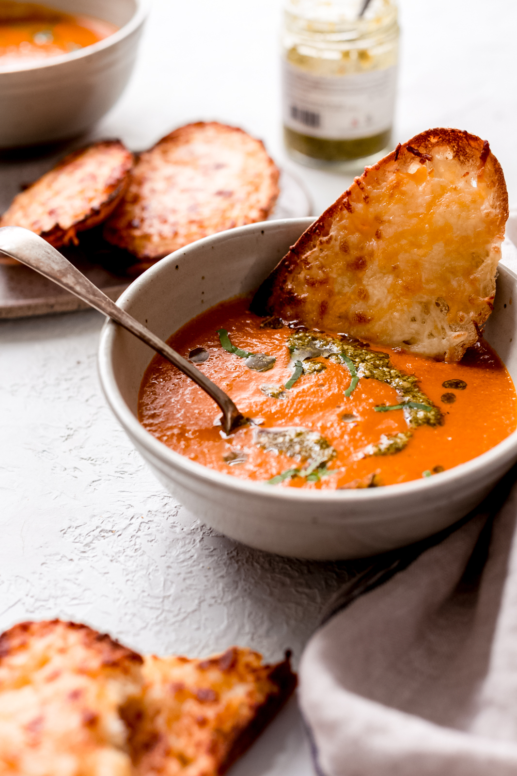 bowl of tomato basil soup with cheese toast and a spoon