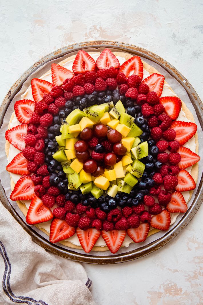 fruit pizza topped with cream cheese icing and fresh fruit